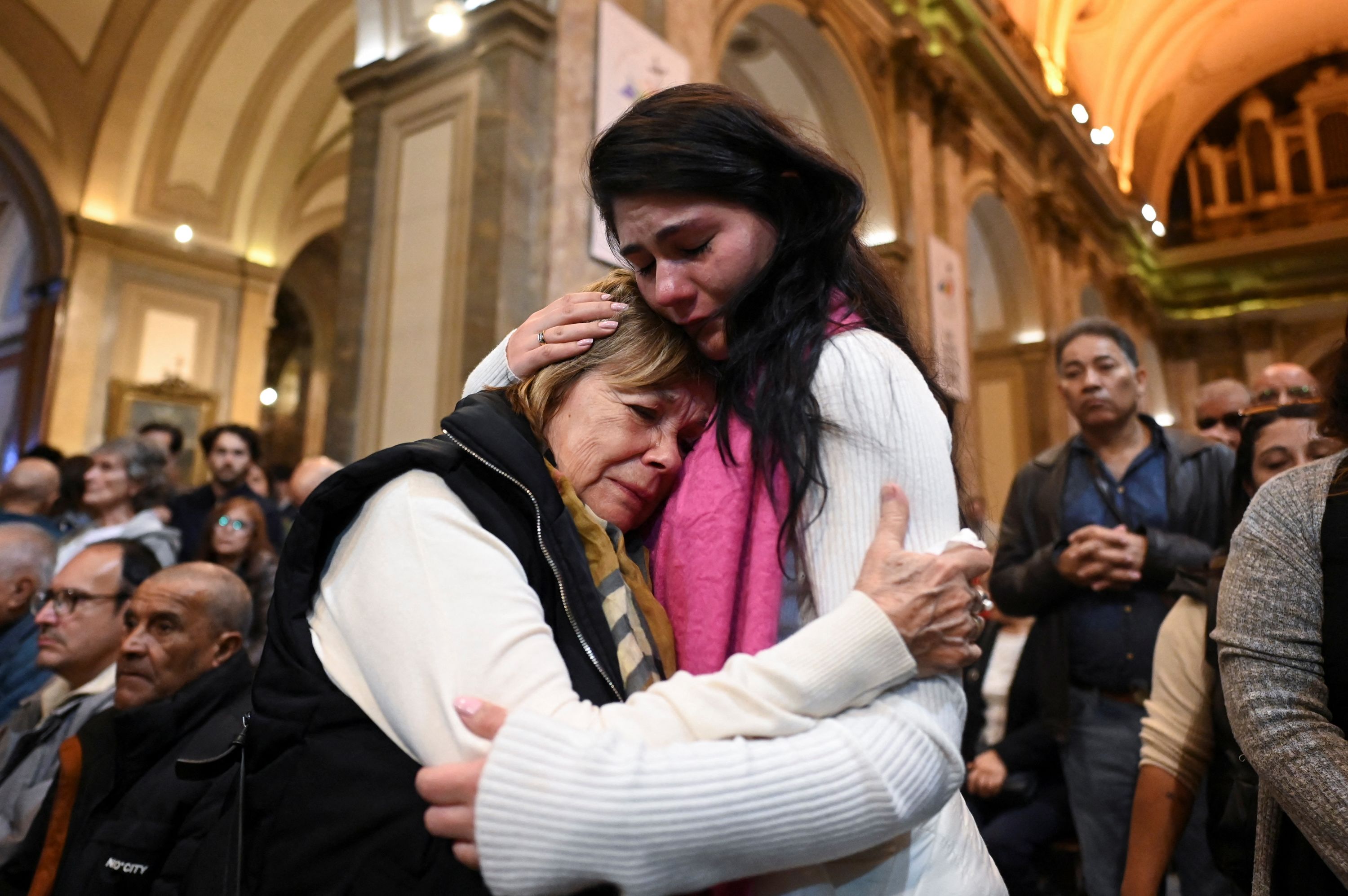People embrace as they attend a Mass in Buenos Aires, Argentina, the birthplace of Pope Francis.