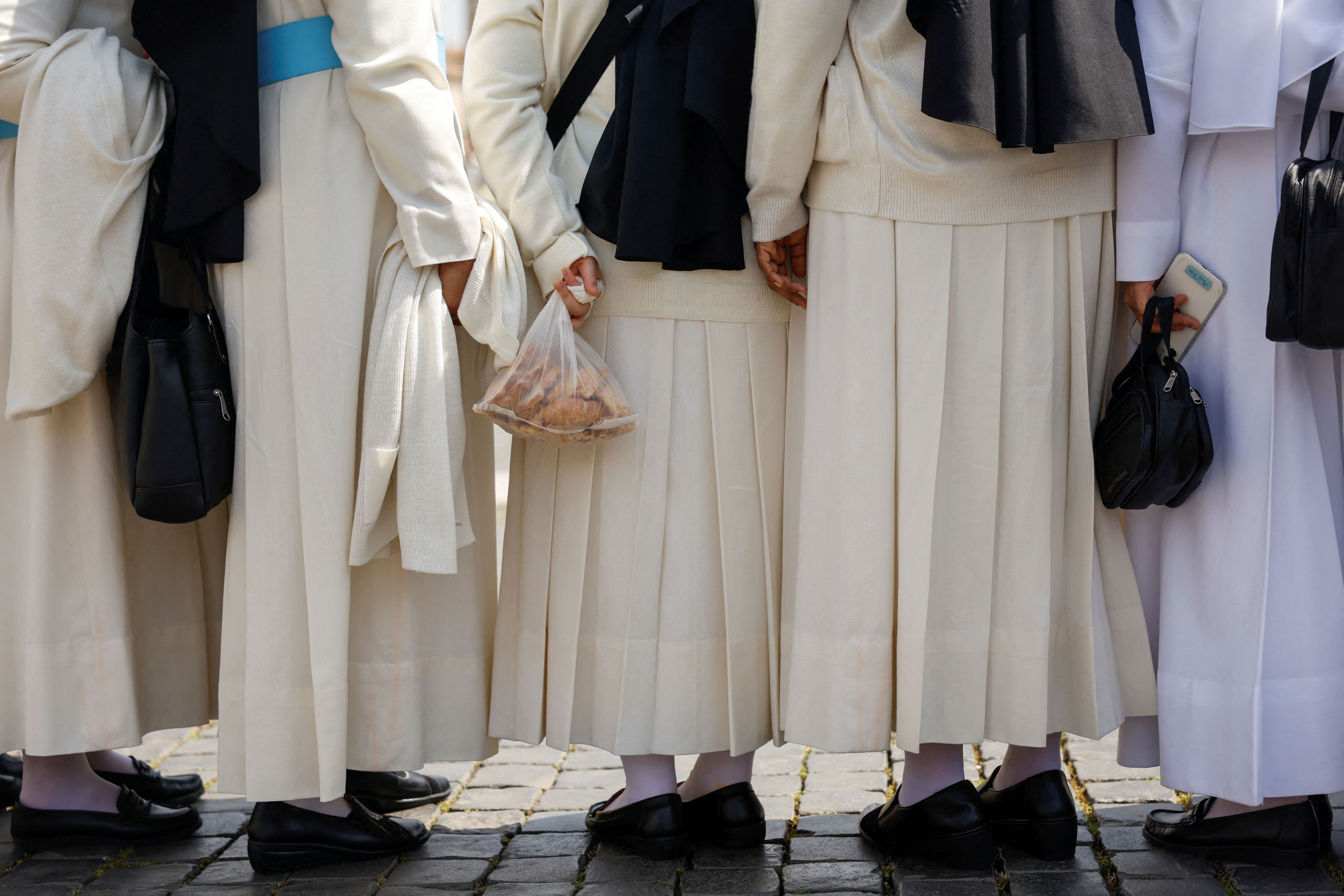 Nuns stand together in St. Peter's Square after paying their respects to the pope.