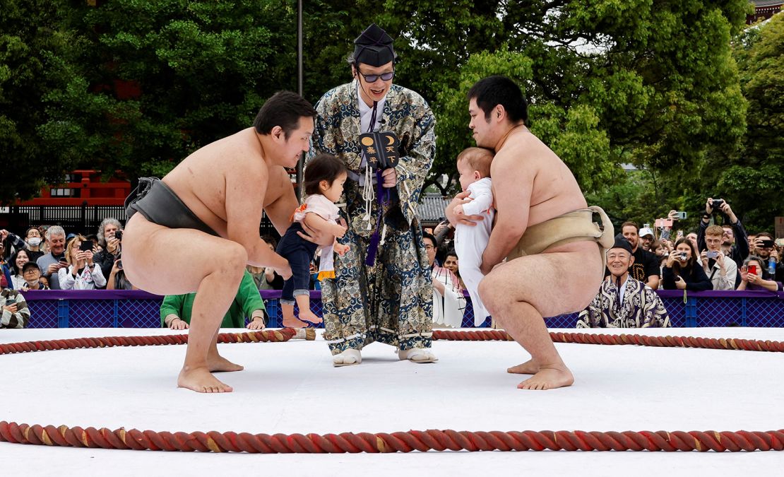 Amateur sumo wrestlers hold babies during 