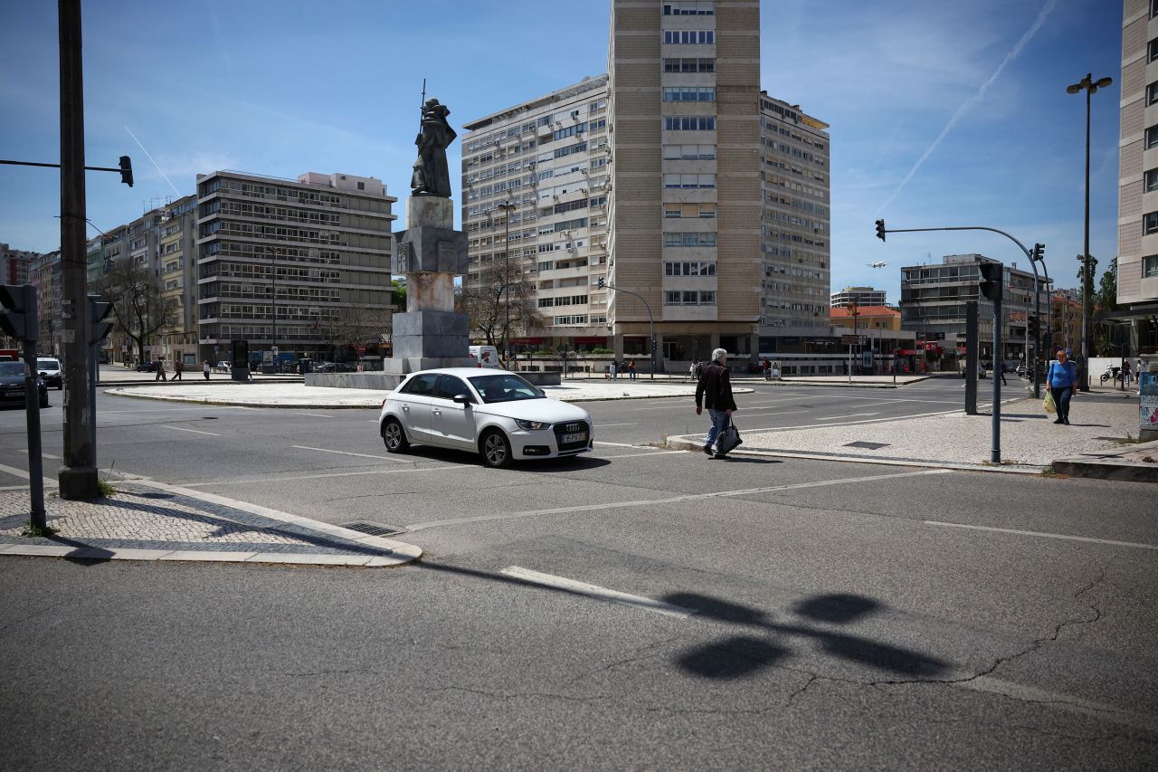 A person walks on a crosswalk as a car passes by during a power outage in Lisbon on Monday.
