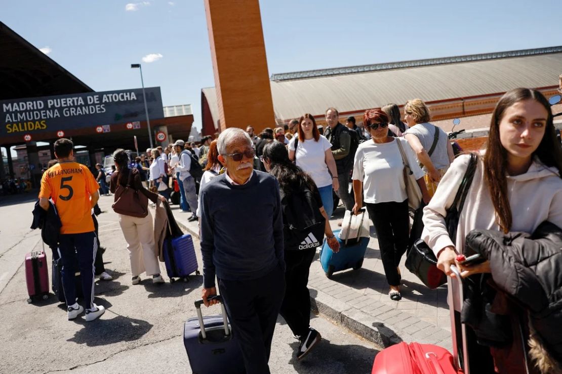 Los viajeros caminan fuera de la estación de tren de Atocha con su equipaje después de que fuera cerrada debido al apagón.
