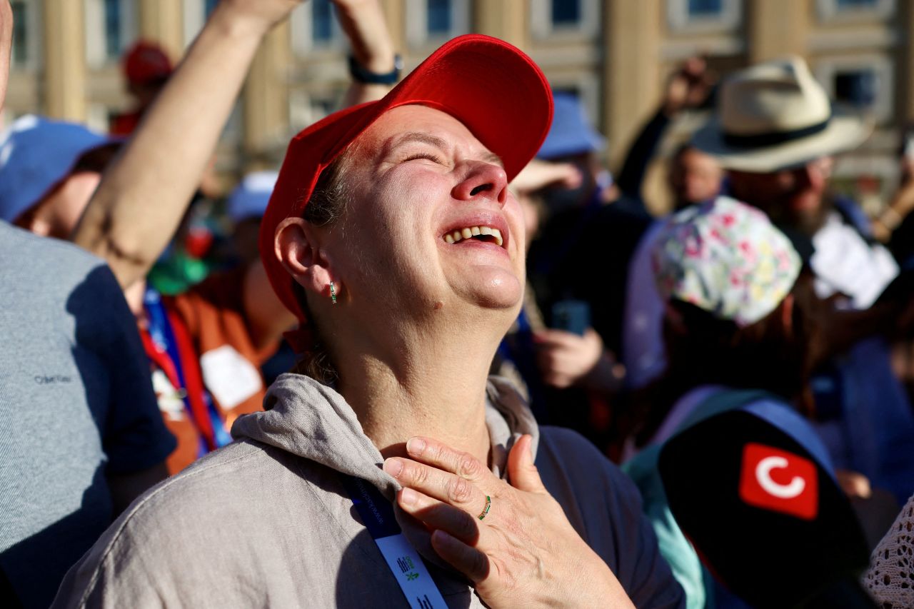A person reacts as white smoke rises from the chimney on the Sistine Chapel.