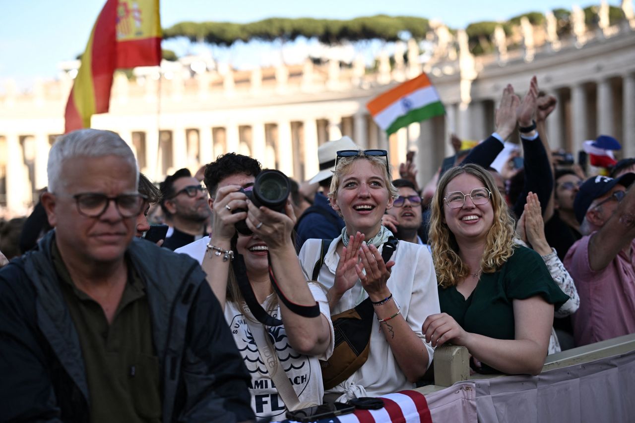 People react as white smoke rises from the chimney on the Sistine Chapel.