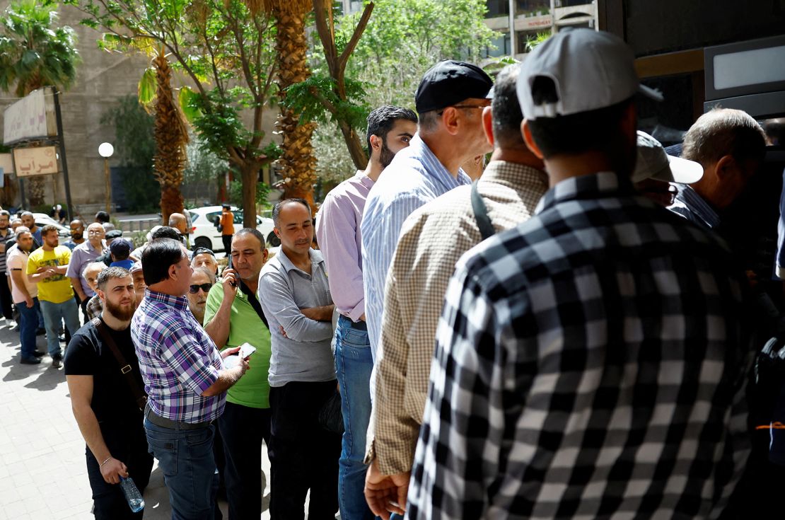 People gather outside the Commercial Bank of Syria, after U.S. President Donald Trump said he would order the lifting of sanctions on Syria, in Damascus, Syria May 14, 2025. REUTERS/Yamam al Shaar