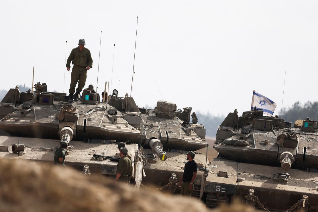 Israeli soliders stand next tanks parked near the Israel-Gaza border, amid the ongoing conflict between Israel and Hamas, in Israel on Monday.