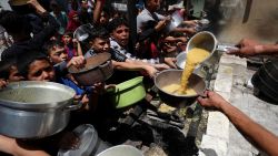Palestinians wait to receive food cooked by a charity kitchen, in Jabalya, in northern Gaza, on May 19, 2025.