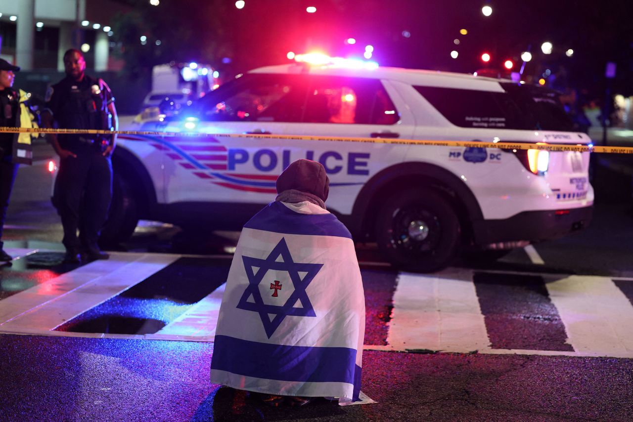 A man kneels at the site of a shooting that killed two Israeli embassy workers, near the Capital Jewish Museum in Washington, DC, late Wednesday night.
