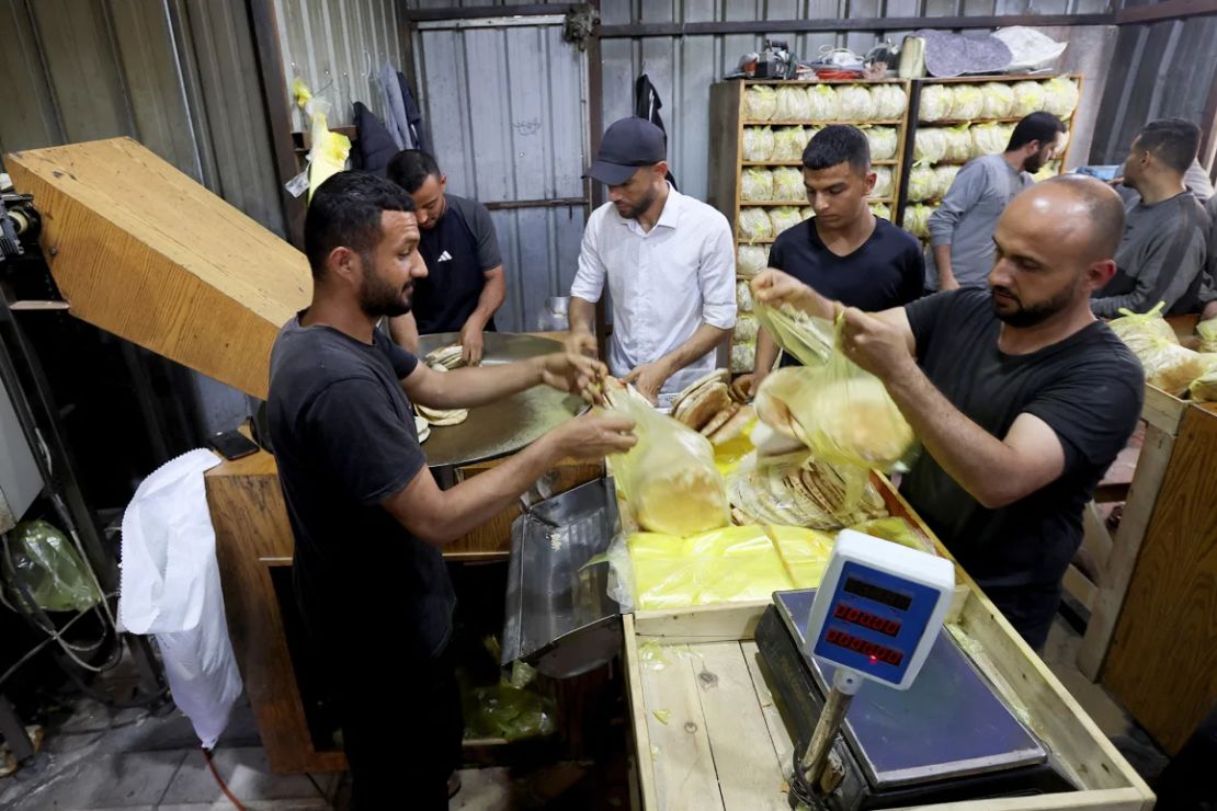 Trabajadores palestinos empacan pan en la misma panadería en Deir Al-Balah.