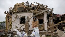 A woman stands with her belongings,  outside her house in Markhalivka, in the Kyiv region of Ukraine, that was destroyed in a Russian strike on Sunday.