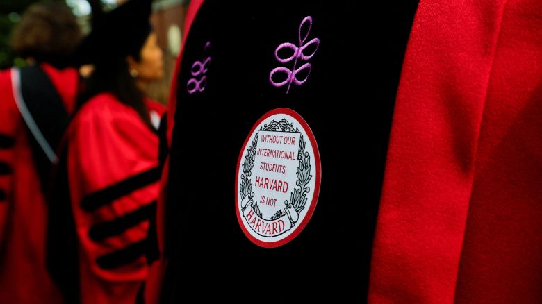 An attendee wears a sticker that reads "Without our international students, Harvard is not Harvard" at commencement exercises that unfolded during federal hearing over student visa program.