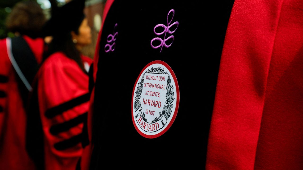 An attendee wears a sticker that reads "Without our international students, Harvard is not Harvard" at commencement exercises that unfolded during federal hearing over student visa program.