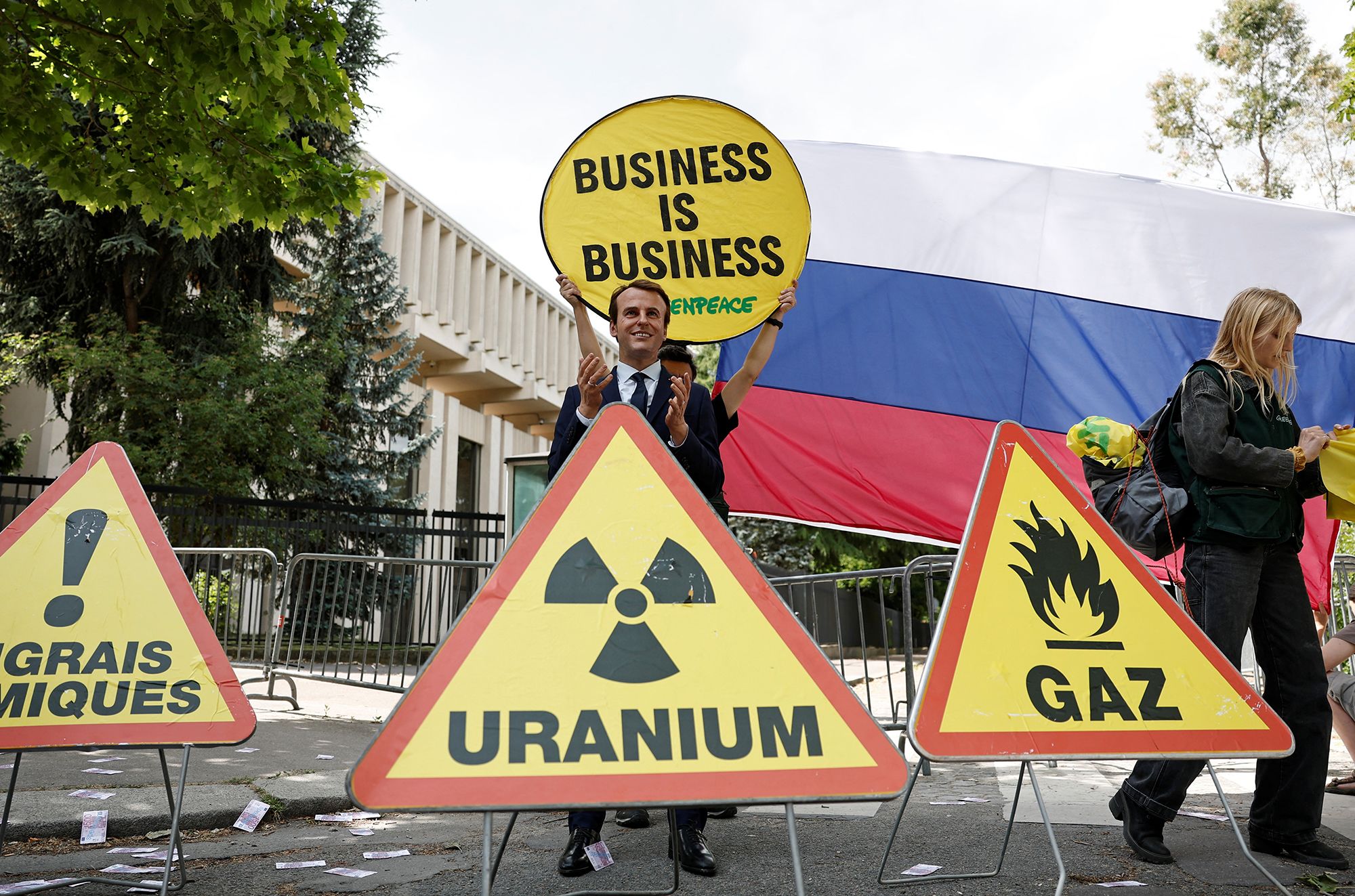 Activists pictured with signs protesting French President Emmanuel Macron's policies toward Russia.