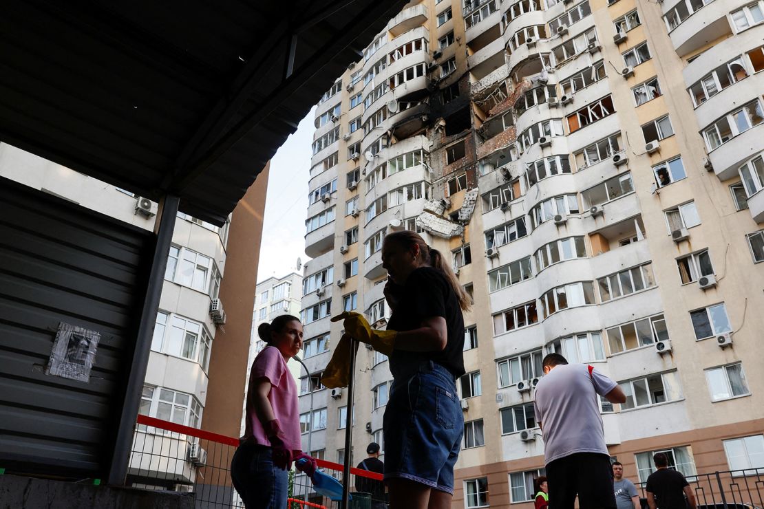 Locals clean up after a Russian drone struck an apartment building in Kyiv on Friday.