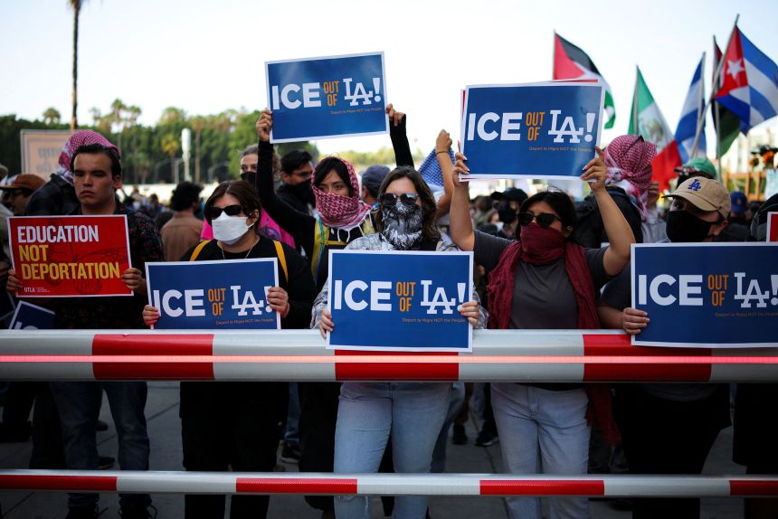 Protestors hold placards as they gather around the Los Angeles Federal Building on Friday.