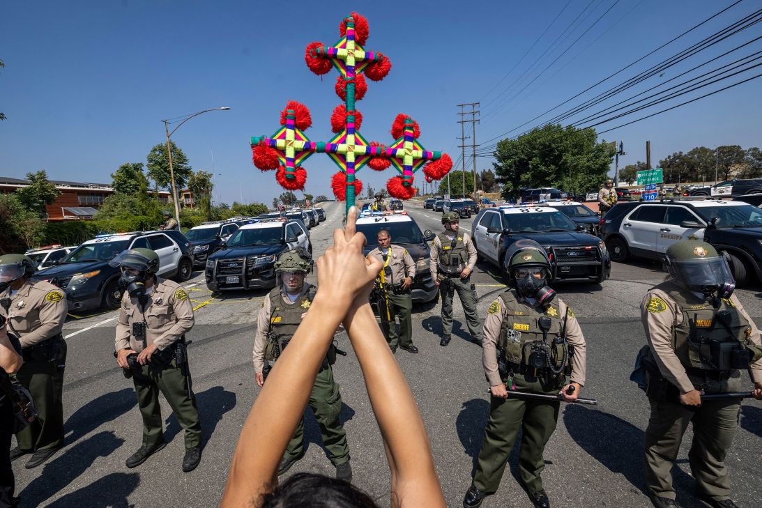 A cross is held aloft near Los Angeles County Sheriff's deputies in Paramount on Saturday.
