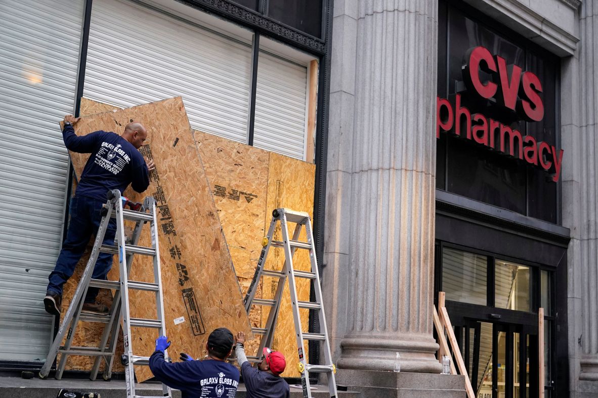 Workers board up a CVS Pharmacy on Tuesday after it was looted following days of protests.