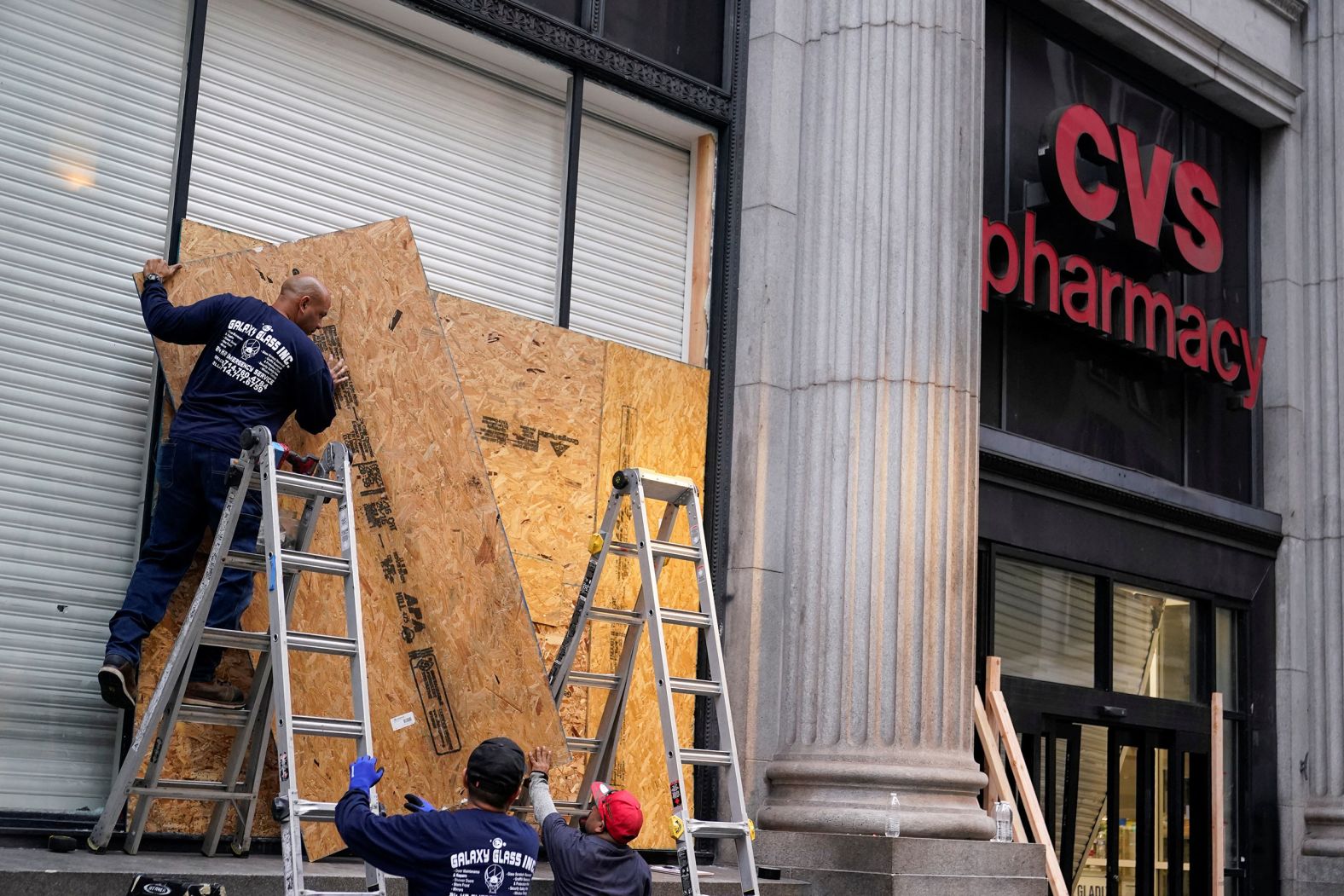 Workers board up a CVS Pharmacy on Tuesday after it was looted following days of protests.