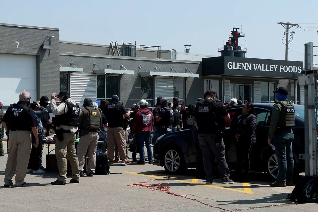 Federal agents stand with workers during a raid by ICE at a meat production plant in Omaha on June 10.
