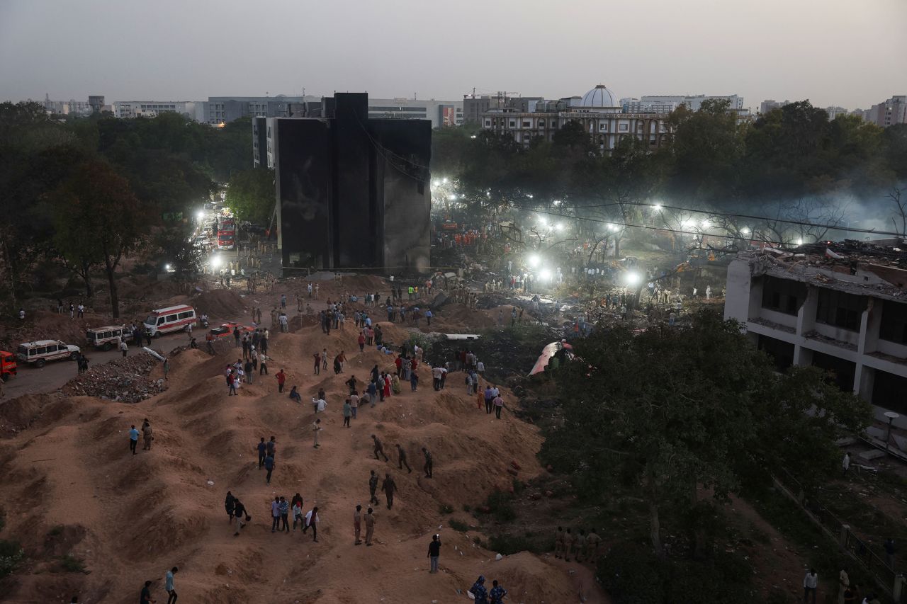 People gather as rescue team members work at the plane crash site in Ahmedabad, India, on Thursday.
