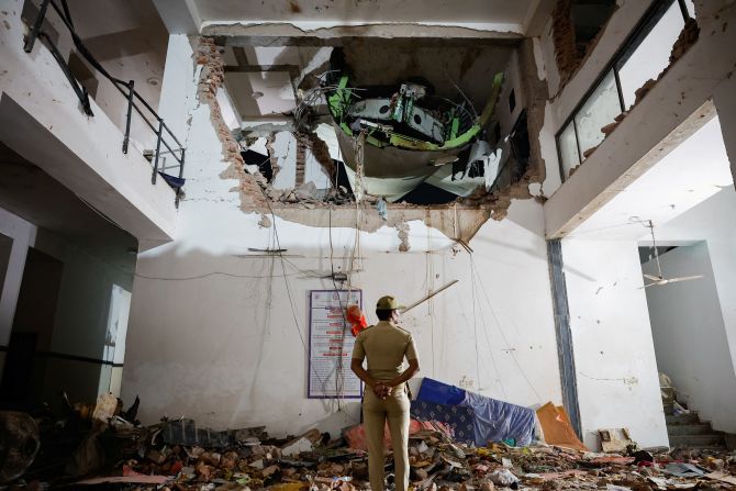 A police officer stands in front of the wreckage.