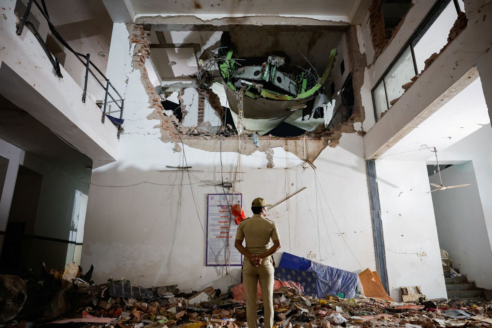 A police officer stands in front of the wreckage.