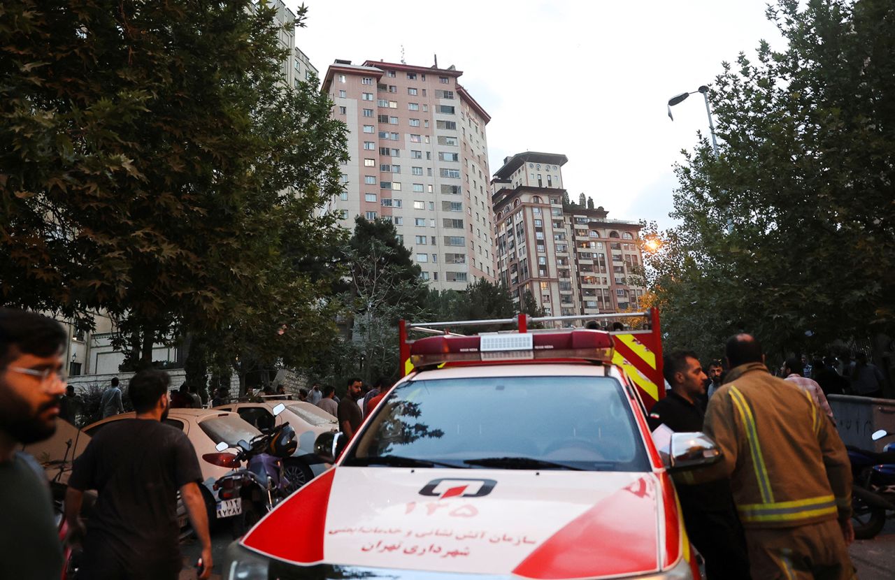 People gather in the street near an emergency vehicle in the aftermath of Israeli strikes, in Tehran, Iran, on Friday.