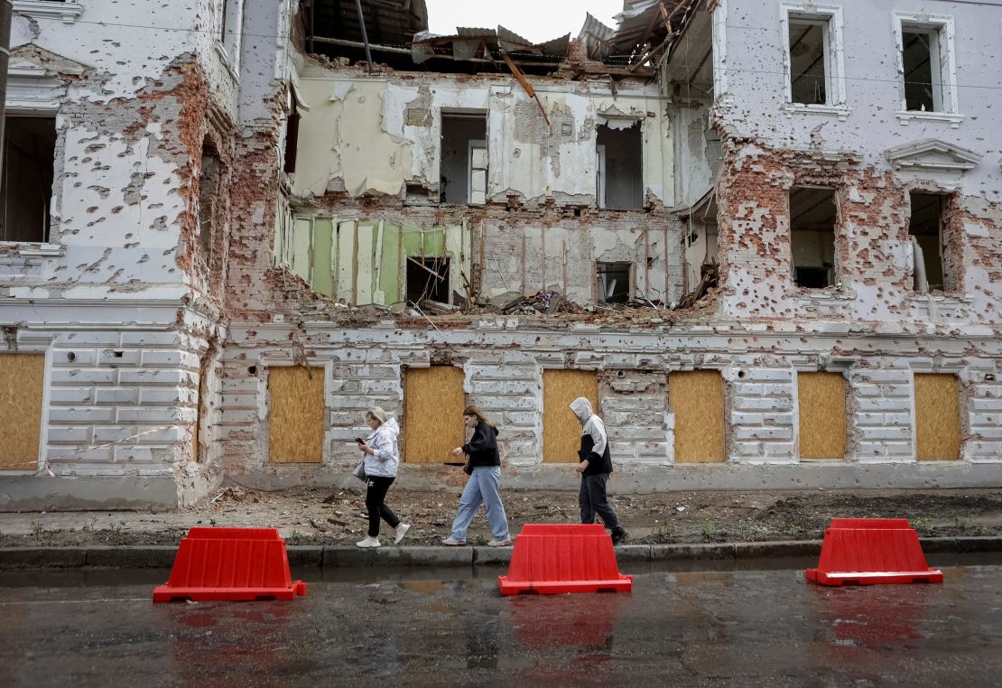 Residents walk at a street near a building damaged by Russian missile strikes, amid Russia's attack on Ukraine, in Sumy, Ukraine June 13, 2025.