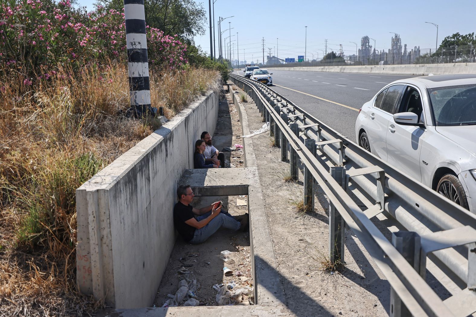 People take shelter at the side of a highway near Sha'ar HaGai, Israel, as sirens sound.