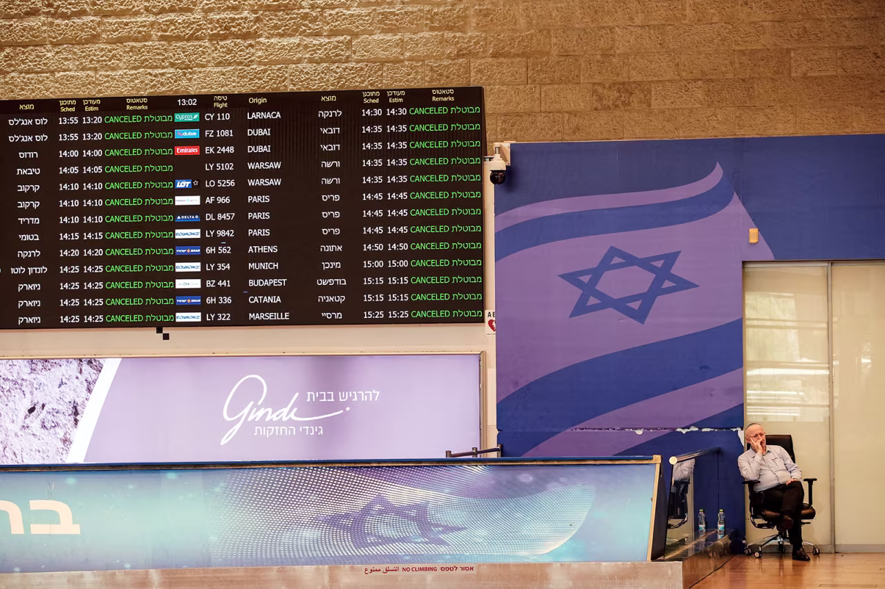 A worker at Ben Gurion International Airport in Israel sits at the arrivals terminal as all flights from and to the airport are indicated cancelled on June 13, 2025.