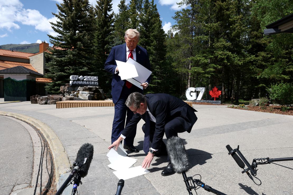 British Prime Minister Keir Starmer helps President Donald Trump pick up trade agreement papers that Trump dropped at the G7.