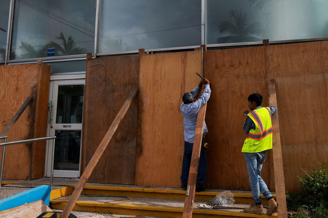 People cover a building with planks of wood as hurricane Erick strengthens off Mexico's Pacific Coast, in Acapulco, Mexico, on Wednesday, June 18, 2025.