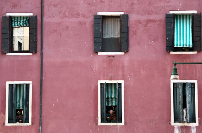 A woman looks out of a window in Venice on Sunday, June 22.