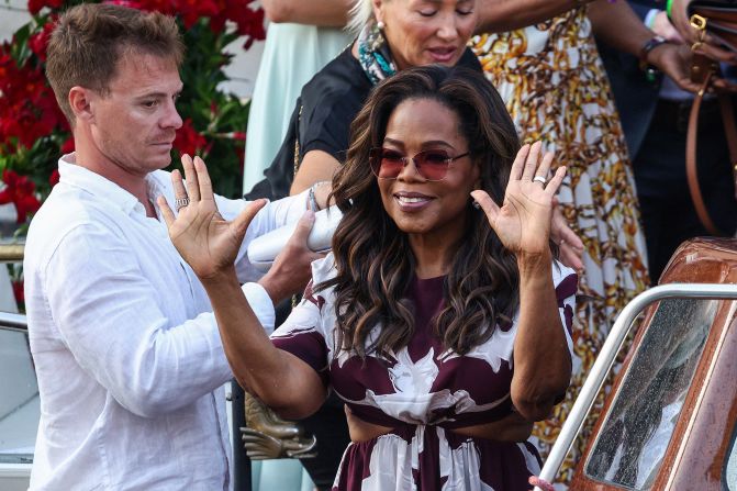 Oprah Winfrey waves before departing the Gritti Palace hotel on Thursday wearing in a cut-out Solace London dress.
