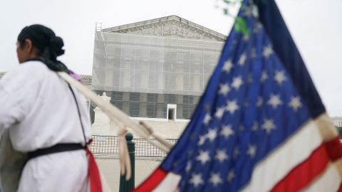 A person stands with a U.S. flag attached to them, after the U.S. Supreme Court dealt a blow to the power of federal judges by restricting their ability to grant broad legal relief in cases as the justices acted in a legal fight over President Donald Trump's bid to limit birthright citizenship, outside the court in Washington, D.C., U.S., June 27, 2025. REUTERS/Nathan Howard