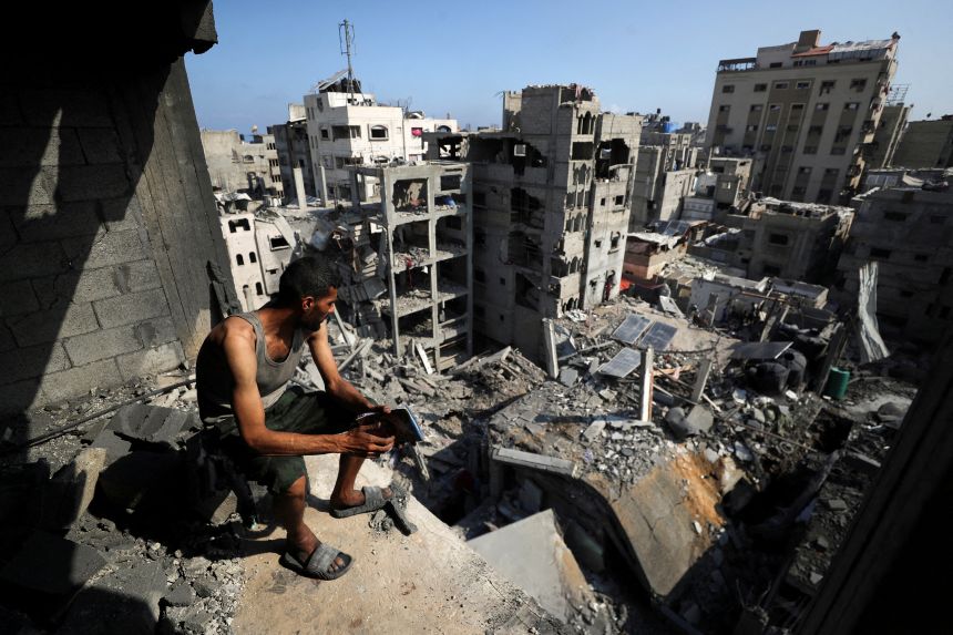 A Palestinian looks on at the site of an Israeli strike last month that damaged and destroyed residential buildings.