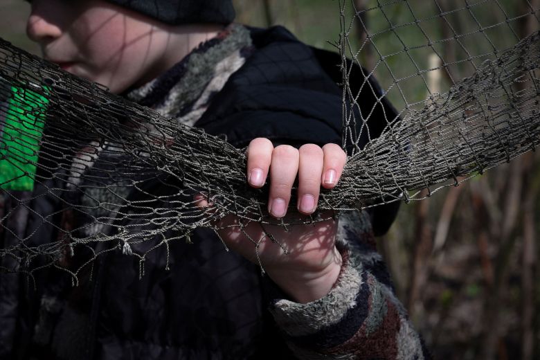 Maksym Tupkalenko, 6, holds the net of a makeshift fort he made with other children in the frontline village of Kalynove in the Kharkiv region of Ukraine, on April 11. The children often pretend to be soldiers tasked with protecting the village, including with their own anti-drone netting.