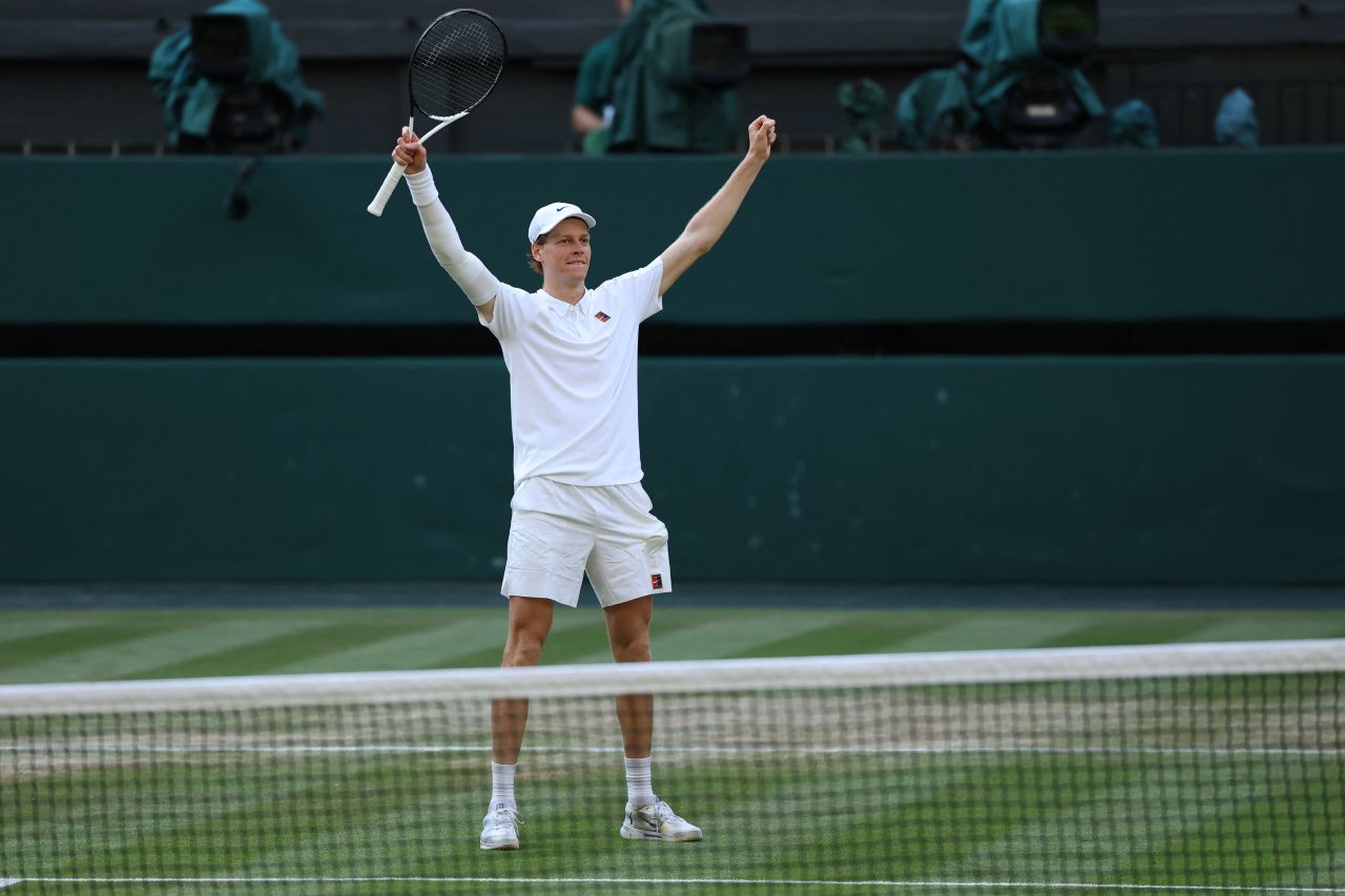 Jannik Sinner raises his arms in victory.