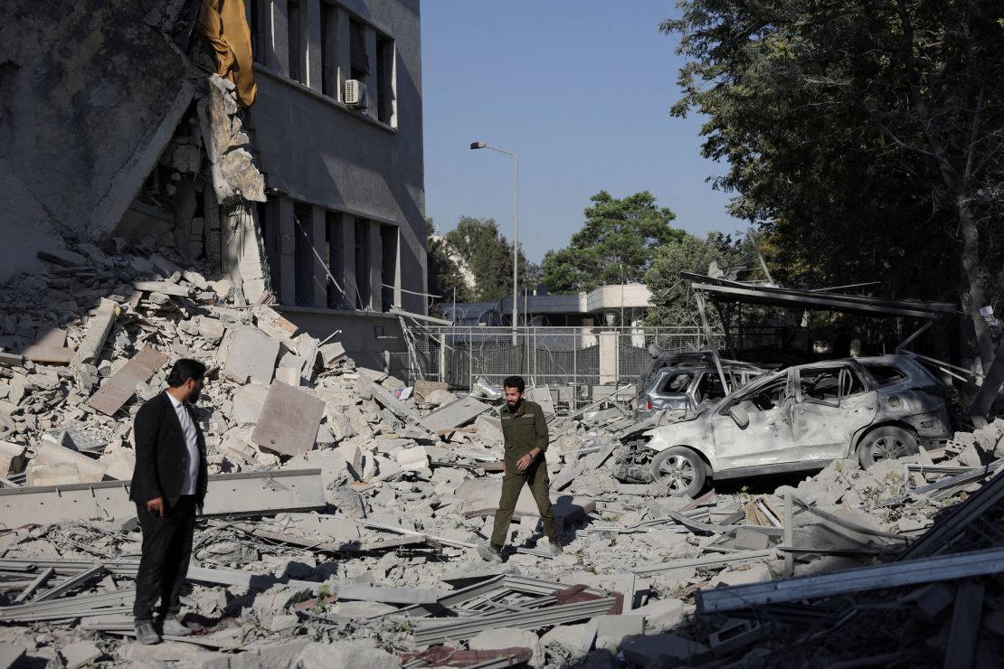 People walk among debris from the airstrikes in Damascus on Wednesday.