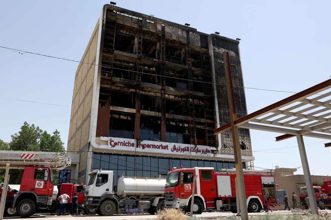 Fire trucks stand next to the wreckage of a shopping center on July 17, 2025, after a massive overnight fire killed dozens of people in al-Kut, Wasit province, Iraq.