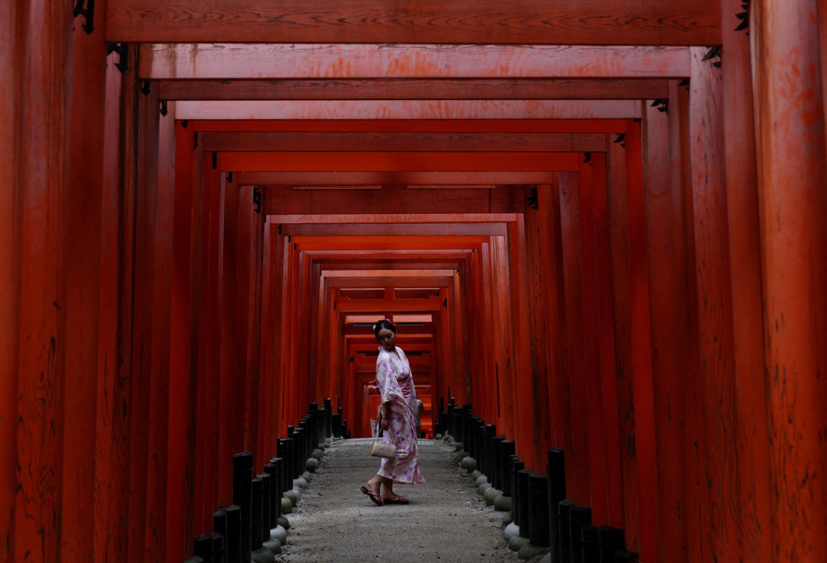 A visitor poses for a photo at the Fushimi Inari Shrine in Kyoto, Japan, on Friday, July 18.