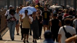 People try to keep cool while walking along the Brooklyn Bridge during a hot and humid day in New York City Friday.