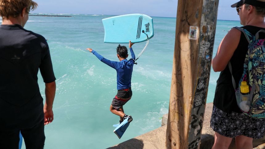 A bodyboarder jumps into water off Waikiki Beach after authorities downgraded earlier tsunami warnings following an earthquake off Russia’s Far Eastern Kamchatka Peninsula, in Honolulu, Hawaii, U.S., July 30, 2025.