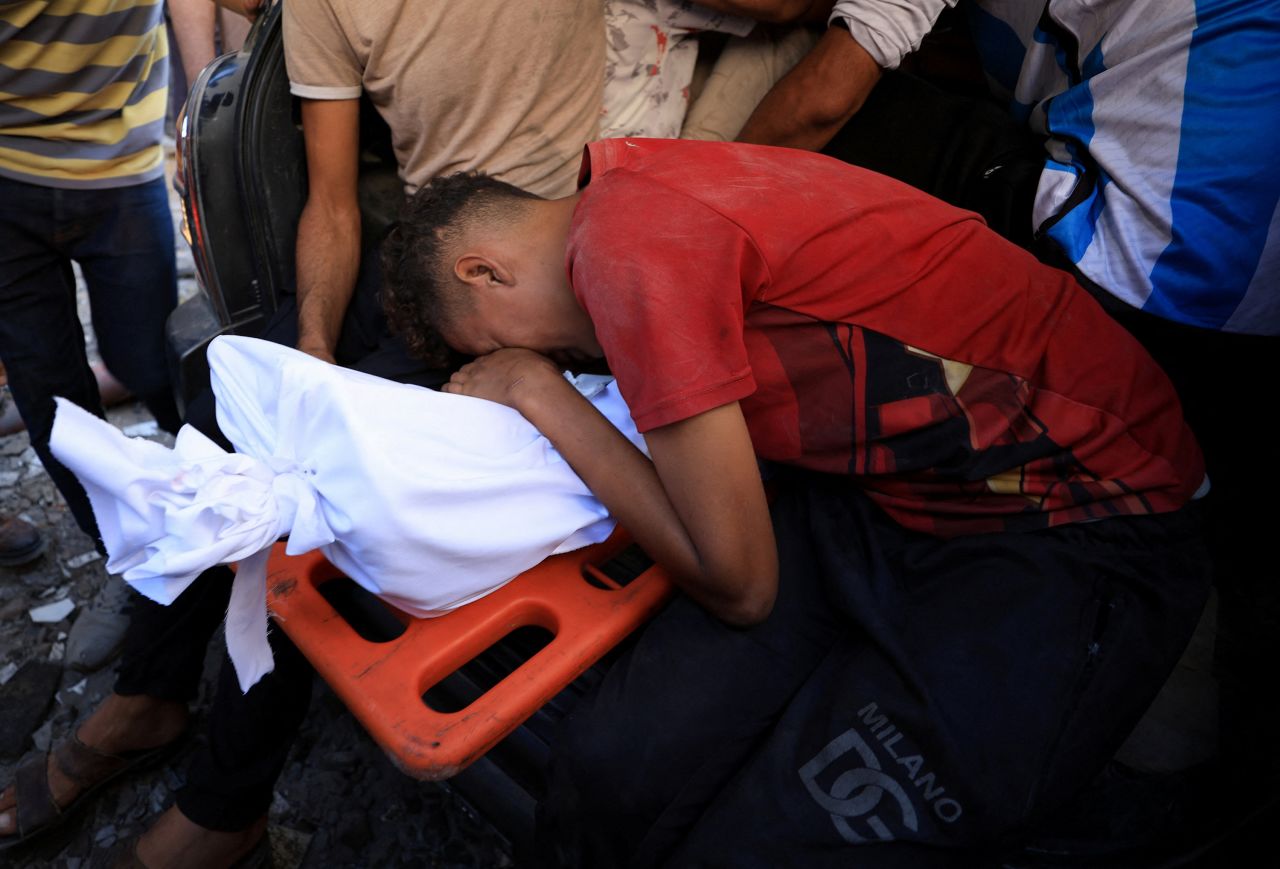 People mourn over a body during the funeral for Palestinians who were killed by Israeli fire while trying to receive aid on Wednesday, and Palestinians who were killed in an overnight Israeli airstrike, in Gaza City on Thursday.