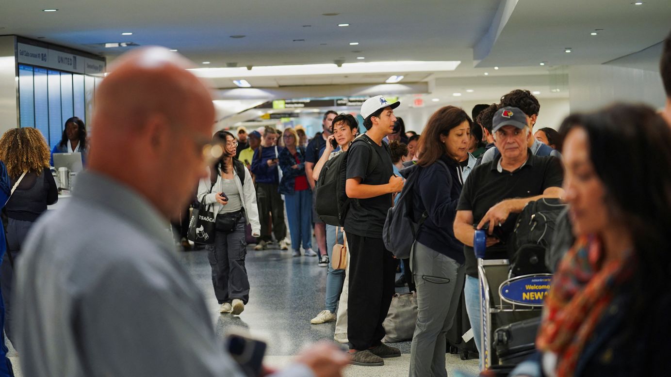 Travelers wait in line for delayed luggage at Newark Liberty International Airport after United Airlines grounded flights because of a tech outage on August 6.