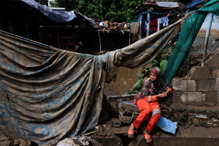 A girl sits outside of her family home, which was damaged following heavy rains and flooding in Pacha Kalay Bazar, in Buner district, Pakistan, on August 18, 2025.