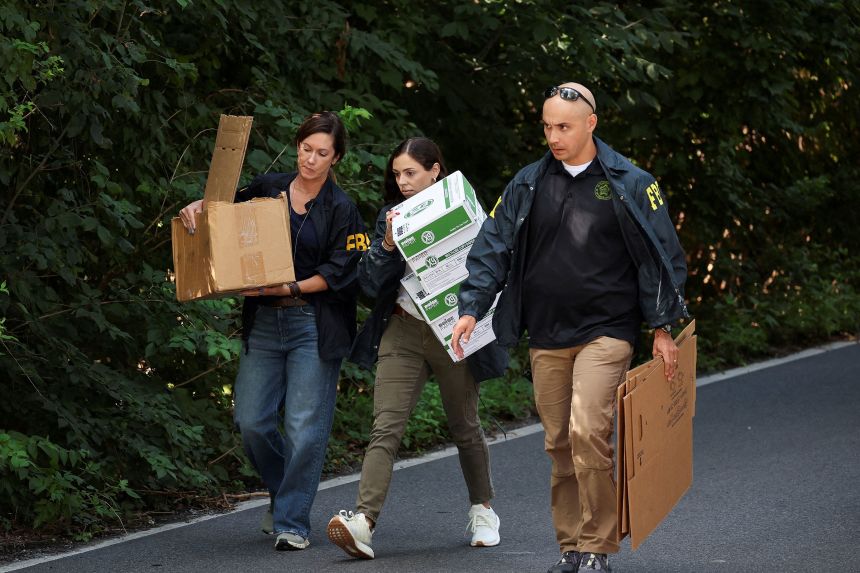 FBI members carry boxes to the home of the former White House national security adviser John Bolton as it is searched by FBI, in Bethesda, Maryland, August 22, 2025.