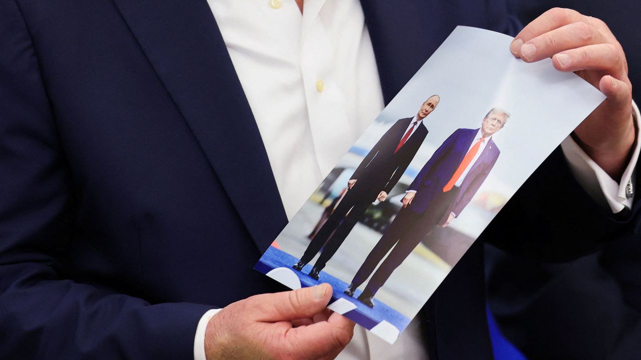 US President Donald Trump holds an image of him and Russian President Vladimir Putin, from their meeting in Alaska, as Trump speaks in the Oval Office of the White House on Friday.