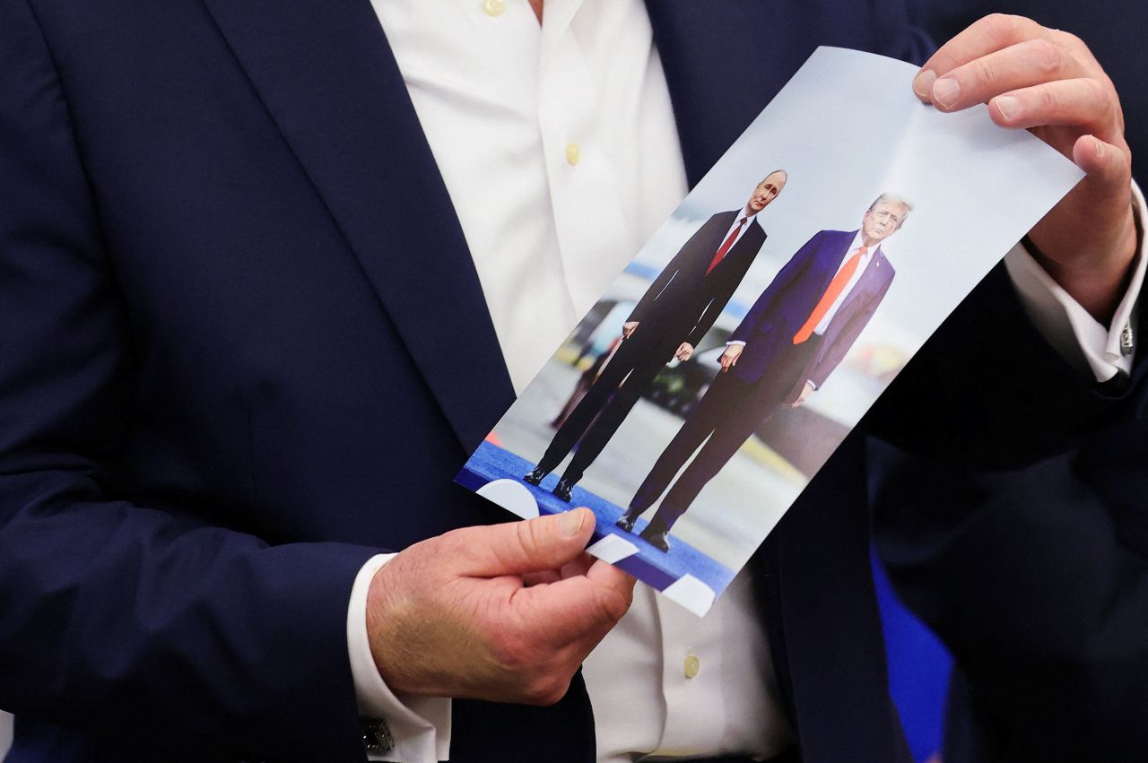 President Donald Trump holds an printed pictured of him and Russian President Vladimir Putin from their meeting in Alaska, in the Oval Office on Friday.
