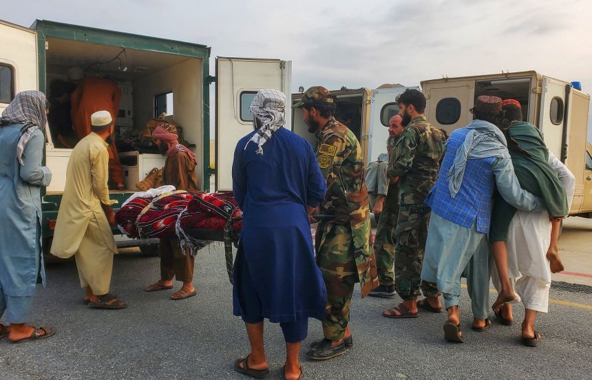 Taliban soldiers and civilians carry earthquake victims to an ambulance at an airport in Jalalabad, Afghanistan, on Monday.
