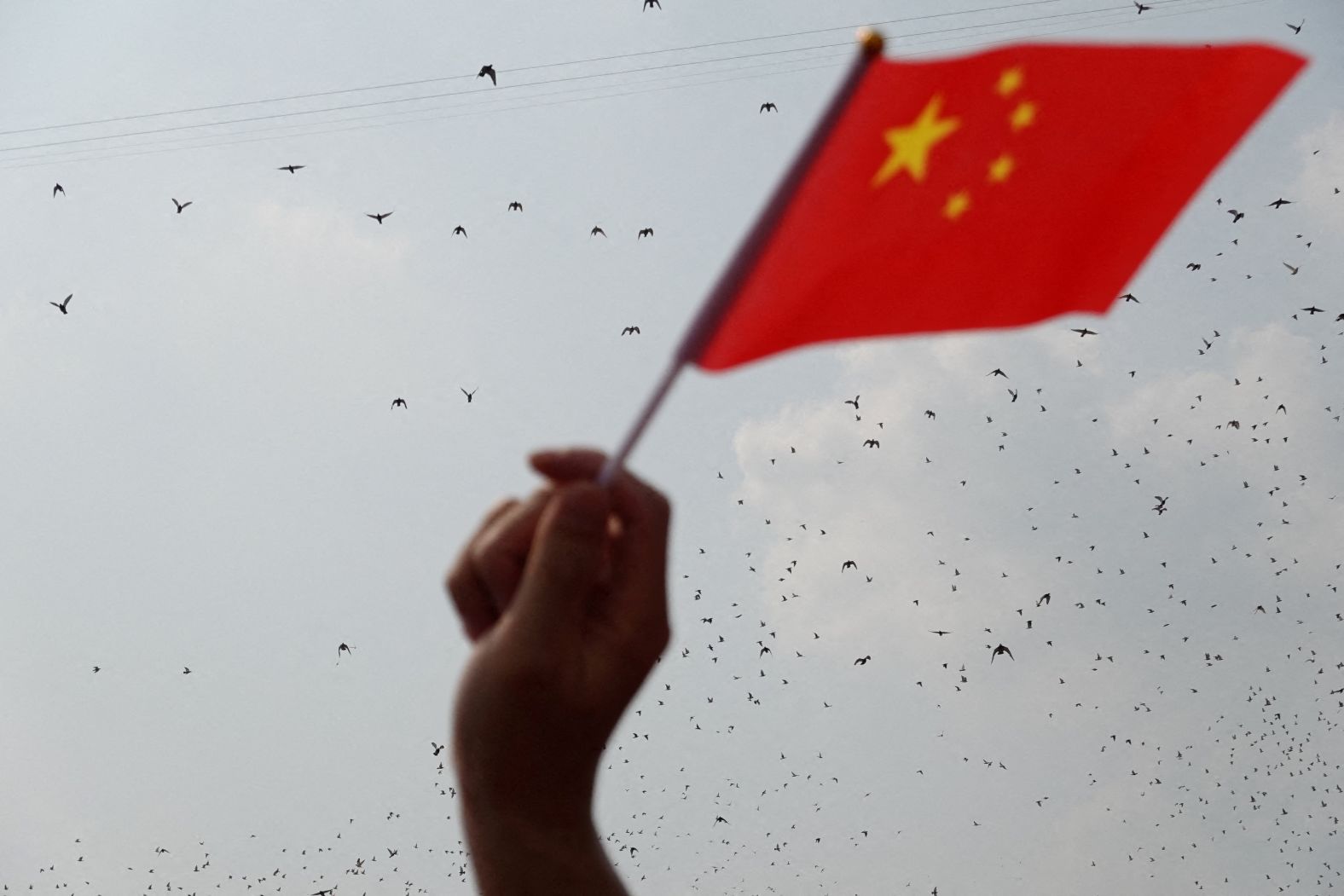 A  Chinese flag waves as doves are released at the end of the parade